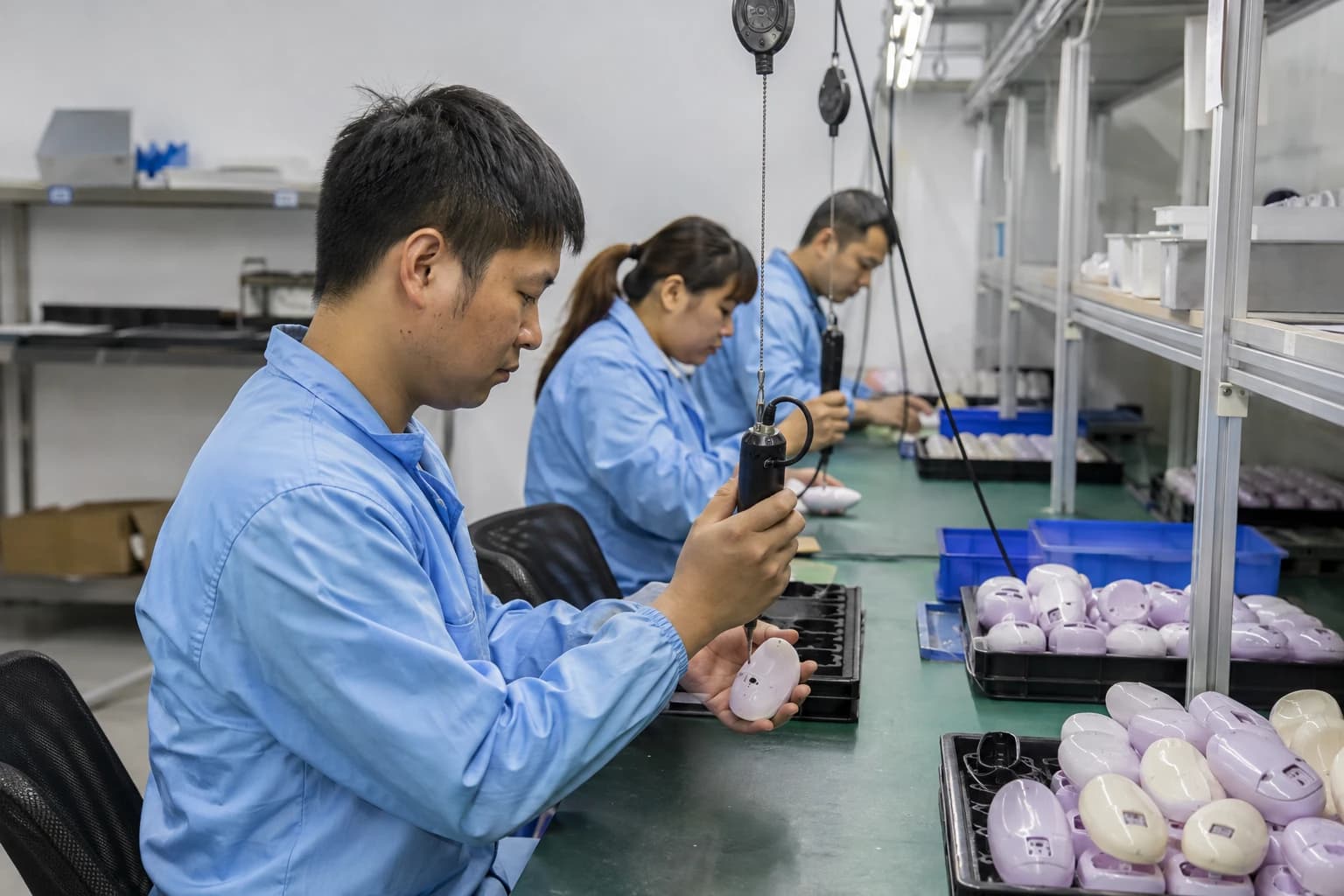 Process illustration of technicians assembling handheld devices at a workbench